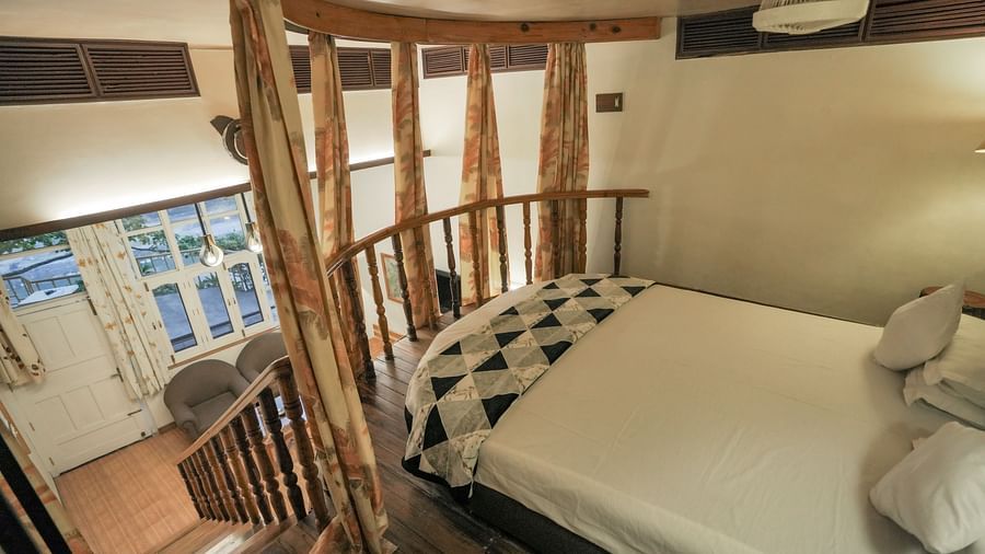 A bedroom with a white bed, a rug, and warm lighting, interior setting with wooden elements - The Den Corbett Resort & Spa, Kumeria.
