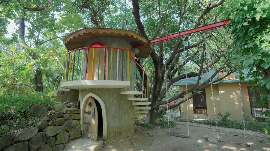 A small building with a curved roof, nestled among tall trees and greenery.