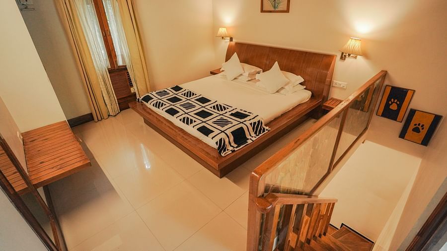 A bedroom with a bed, a chair, and a patterned rug, warm lighting - The Den Corbett Resort & Spa, Kumeria.