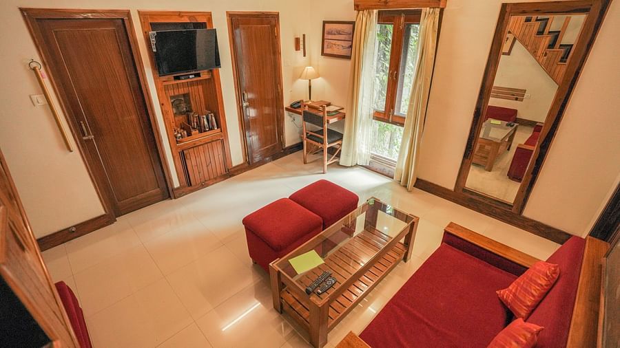 A living room with a couch, a table, and warm lighting, wooden interior - The Den Corbett Resort & Spa, Kumeria.