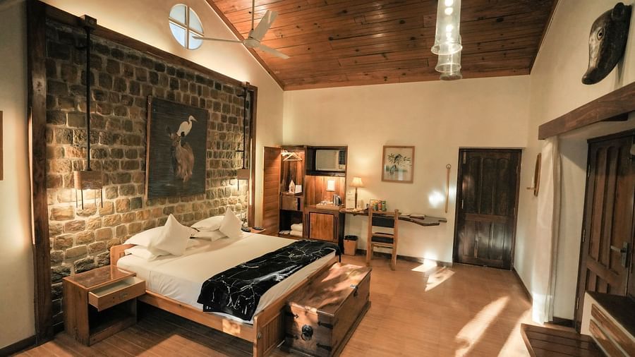 A bedroom with a bed, a patterned rug, and warm lighting, wooden interior - The Den Corbett Resort & Spa, Kumeria.
