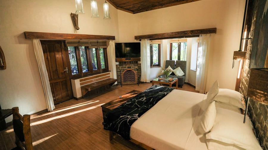 A bedroom with a bed, a lamp, and warm lighting, wooden interior - The Den Corbett Resort & Spa, Kumeria.