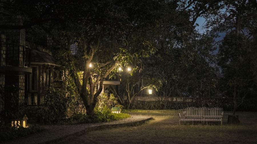 An outdoor path lit by lanterns at night, trees and foliage visible - The Den Corbett Resort & Spa, Kumeria.