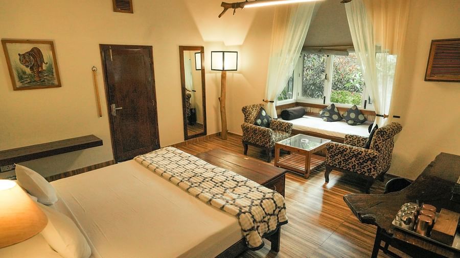 A bedroom with a bed, a lamp, and warm lighting, wooden interior - The Den Corbett Resort & Spa, Kumeria.