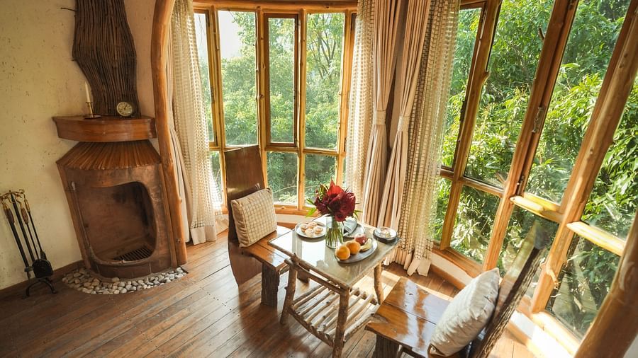 A room with a wooden table and chairs by a large window, warm lighting - The Den Corbett Resort & Spa, Kumeria.