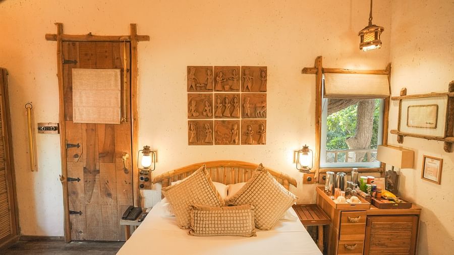 A bedroom with a bed, a lamp, and warm lighting - The Den Corbett Resort & Spa, Kumeria.
