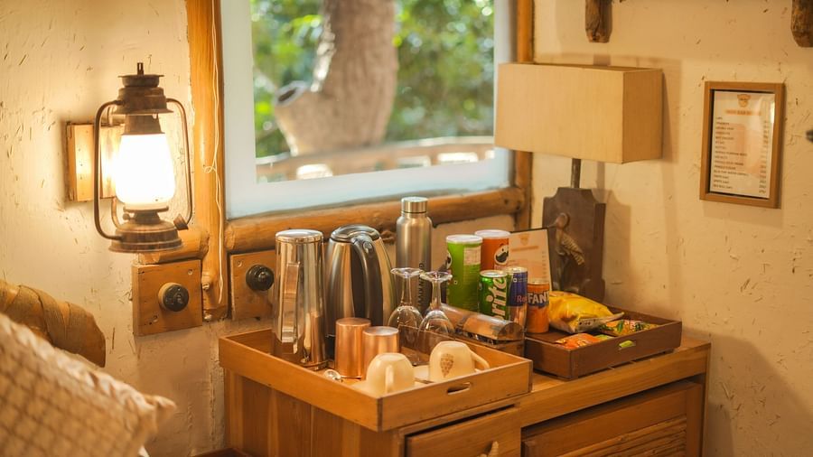 A room with a wooden table, a lamp, and warm lighting, large windows - The Den Corbett Resort & Spa, Kumeria.