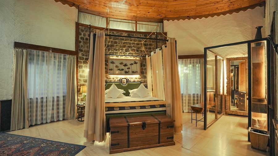 A bedroom with a wooden bed frame, a patterned rug, and warm lighting - The Den Corbett Resort & Spa, Kumeria.