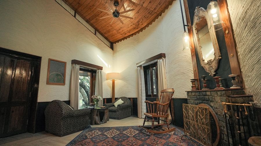 A living room with a patterned rug, a couch, and warm lighting, wooden interior - The Den Corbett Resort & Spa, Kumeria.