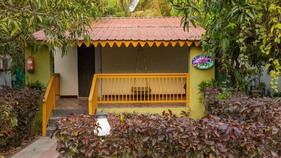 A yellow and green cottage with a red roof surrounded by greenery at Daksh Resort & Amusement Park, Sasan Gir