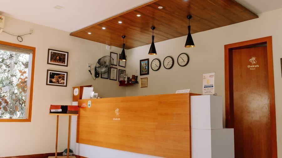 A brightly lit hotel reception area with a wooden desk and walls at Daksh Resort & Amusement Park, Sasan Gir.