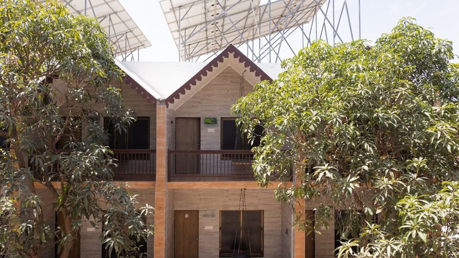 The exterior of Daksh Resort & Amusement Park, Sasan Gir featuring the multi-storey building with sloped roofs surrounded by greenery.