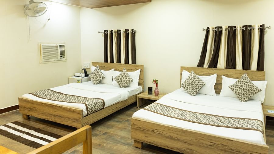A room featuring 2 large beds with matching brown and white bedding at Daksh Resort & Amusement Park, Sasan Gir.