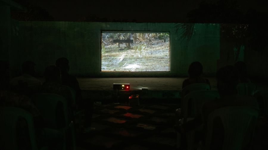 An outdoor theatre setting featuring a film screening on a projector screen with chairs arranged in front at Daksh Resort and Amusement Park.