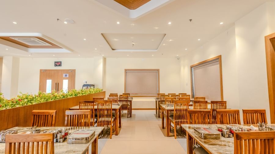 Front view of the pathway at the restaurant of Daksh The Grand Goverdhan, Dwarka, with dining tables on either side of it.