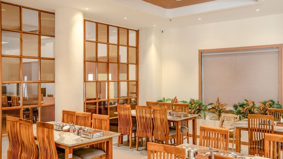 A wide-angle shot of the restaurant at Daksh The Grand Goverdhan, Dwarka, with ample of seating space.
