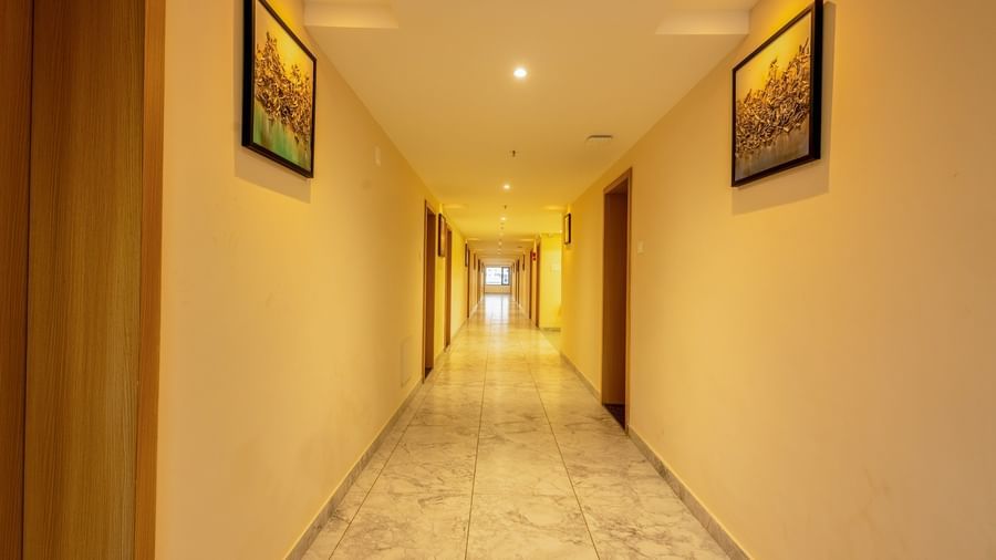 An empty corridor at Daksh The Grand Goverdhan, Dwarka, with various photo frames wall mounted across the hall.