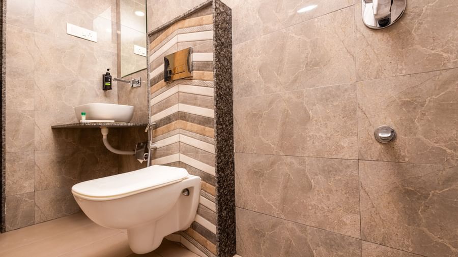 Corner view of a stylish washroom area at Daksh The Grand Gowardhan, Dwarka, featuring a wall-mounted toilet and unique patterned tiles.