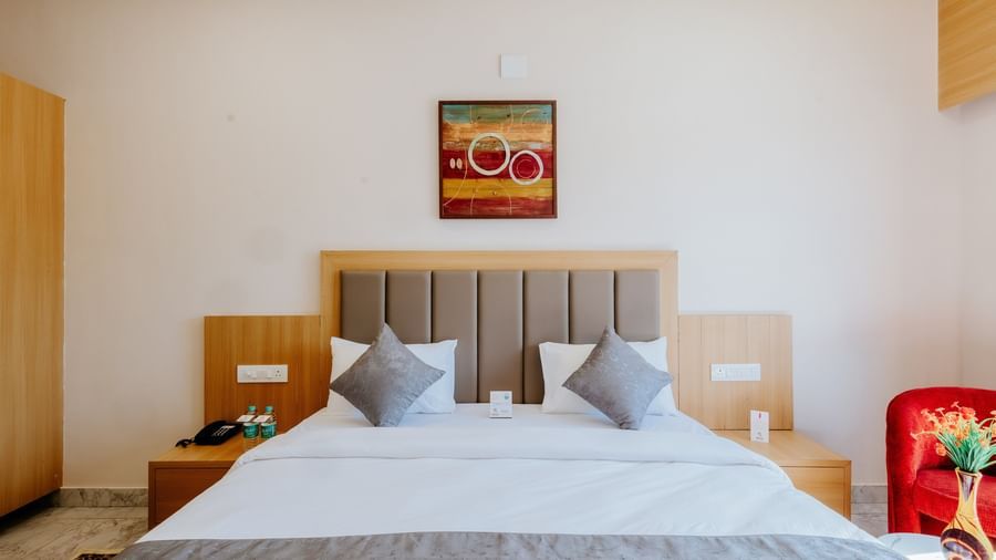 Front view of an inviting bedroom at Daksh The Grand Gowardhan, Dwarka, featuring a plush double bed along with a cushioned headboard.