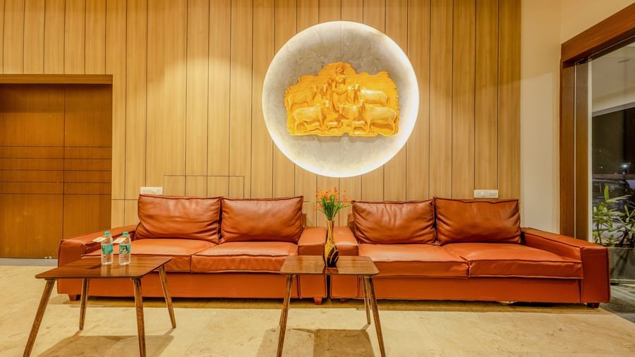 A cosy lounge area at Daksh The Grand Gowardhan, Dwarka, complete with a comfortable sofa and tasteful wall art.