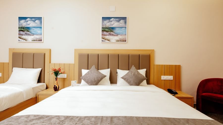 Close up shot of a double bed of the Pride Room at Daksh The Grand Gowardhan, Dwarka, showcasing its clean linen and a decorative art piece hung above it.