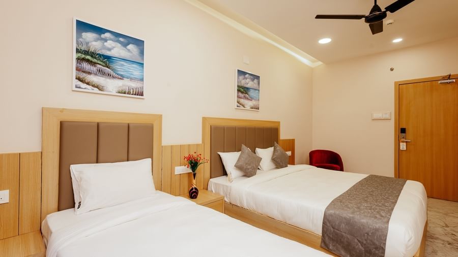 An inviting bedroom at Daksh The Grand Gowardhan, Dwarka, showcasing its clean linen, ample space, and art pieces hung above the bed.