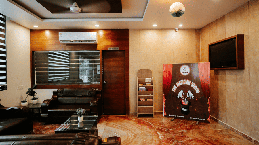 Interior view of a sleek hotel lobby or waiting area with warm lighting. Features marble flooring and modern furniture in black and brown tones at Daksh The Madhuvan Suites, Dwarka.