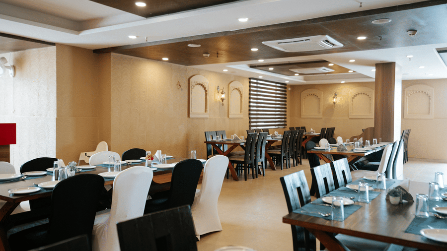 Close-up of the sleek, modern buffet serving area with a long counter, chafing dishes, and bright blue ambient lighting at Daksh The Madhuvan Suites, Dwarka.