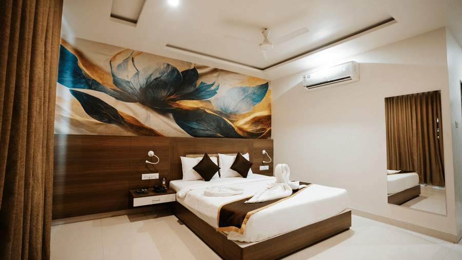 Detail of the room's media unit: wall-mounted TV, white desk, storage drawers, and a black office chair in a corner at Daksh The Madhuvan Suites, Dwarka.