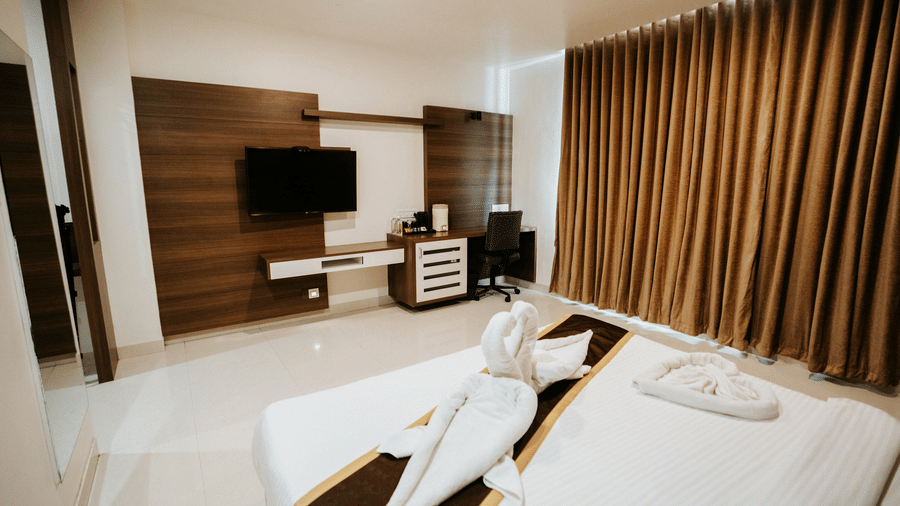 Spacious hotel room featuring a large, abstract floral painting above the bed, modern dark wood fittings, and white tiled floor at Daksh The Madhuvan Suites, Dwarka.