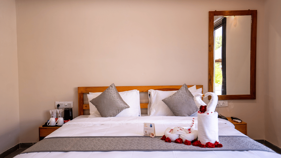 A close-up of a double bed decorated with towel art and flower petals, perfect for a special stay - Daksh The Nirvana Retreat, Pavagadh