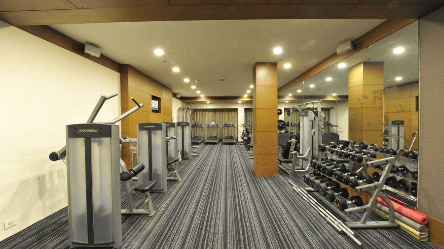 Modern gym with various workout machines and equipment at Narayani Heights Hotel & Resorts, Ahmedabad.