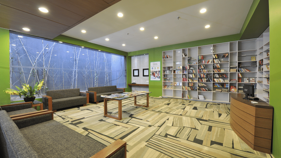 Spacious lounge area with plush seating and a large bookshelf – Narayani Heights Hotel & Resorts