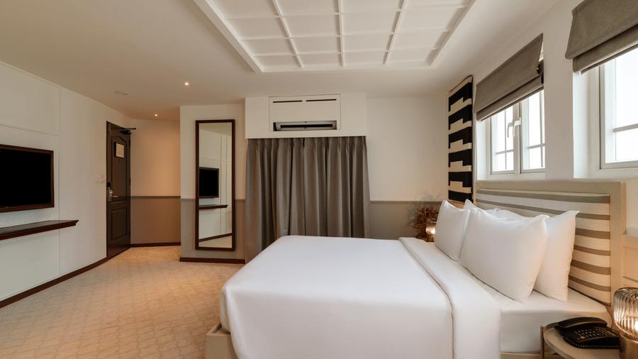 Deluxe Room at Shilton Suites, Bengaluru, featuring a king size bed, bedside tables, work desk and large windows.