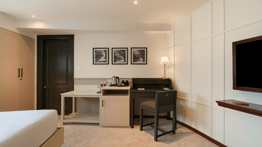 Deluxe Room at Shilton Suites, Bengaluru, featuring a king size bed, bedside tables, work desk, wall mounted television and framed artwork.