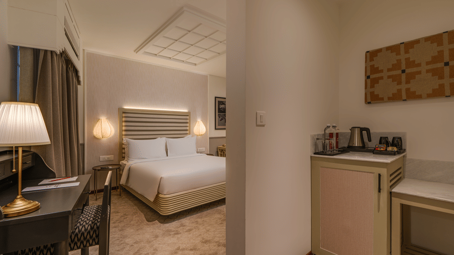 Executive Queen Room at Shilton Suites, Bengaluru, featuring a king size bed, bedside tables, work desk, floor lamp and wardrobe.
