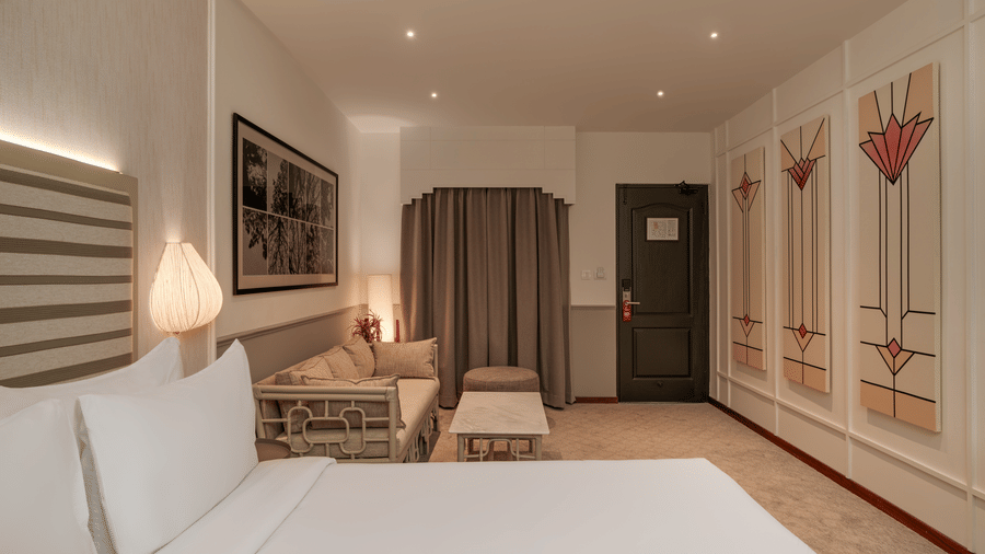 Executive Queen Room at Shilton Suites, Bengaluru, featuring a king size bed, bedside tables, armchair, work desk, wardrobe and entryway.