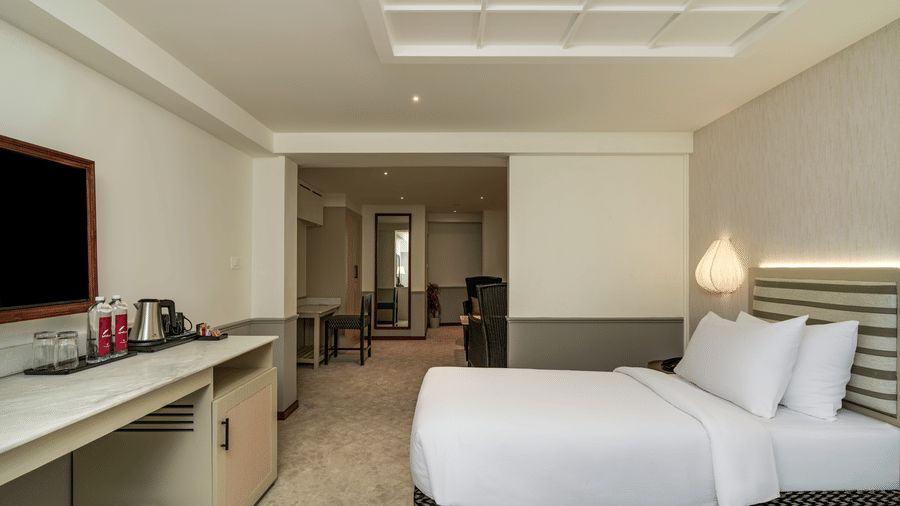 Executive Twin Room at Shilton Suites, Bengaluru, featuring twin beds, bedside tables, wall mounted television, work desk and seating area.