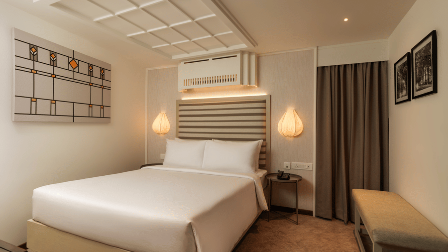 Superior Room at Shilton Suites, Bengaluru with a king size bed, bedside tables, wall mounted television and comfortable seating area.