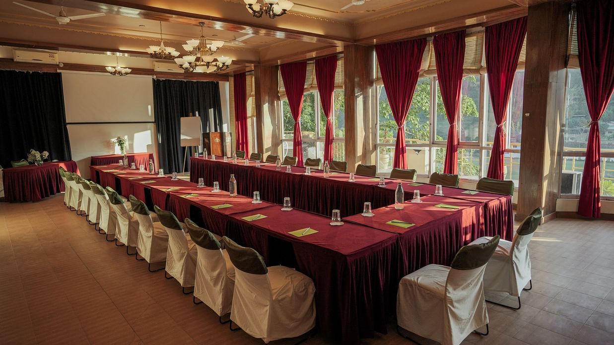 A room with drapes and tables set in a U-shape, possibly for a meeting or event.