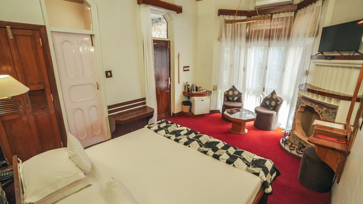 A bedroom with a bed, a rug, and warm lighting, interior setting - The Den Corbett Resort & Spa, Kumeria.