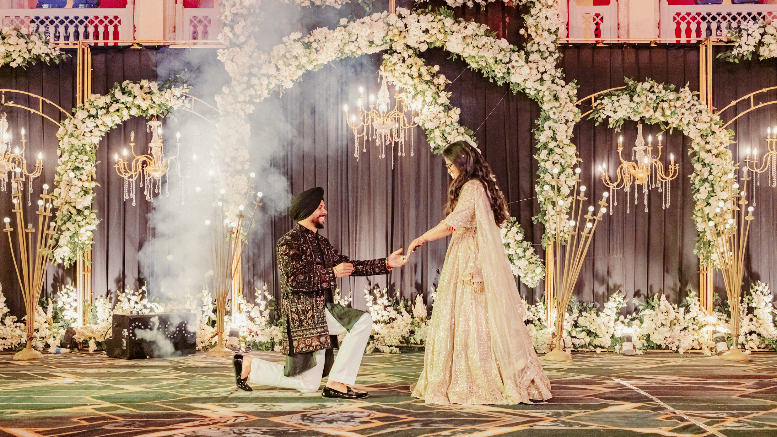 Jaswinder and Ritika performing wedding ritual under floral arch at Umaid Palace.