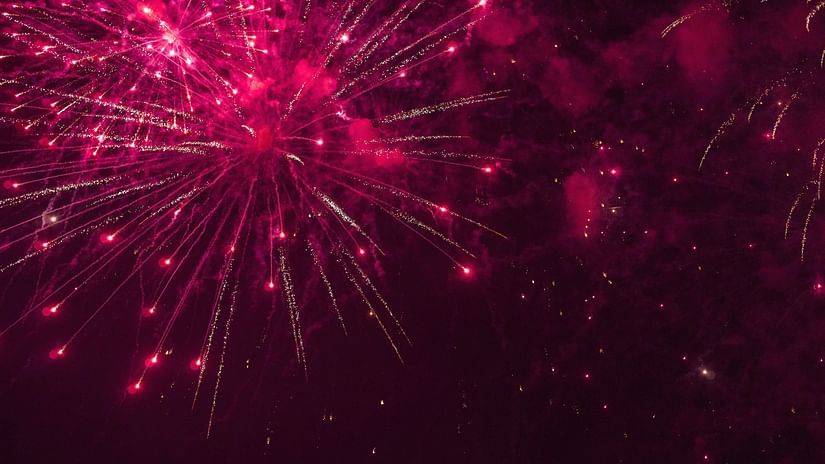a close up shot of pink coloured fireworks lighting up the night sky 