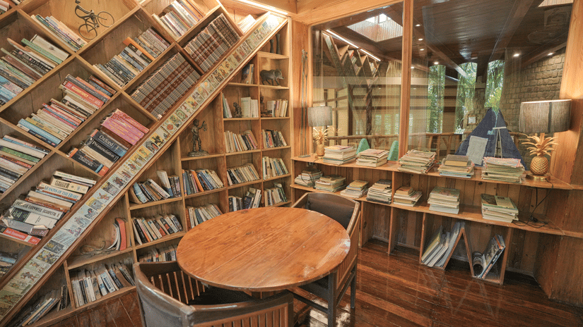 A room filled with bookshelves, a round wooden table, and warm lighting.