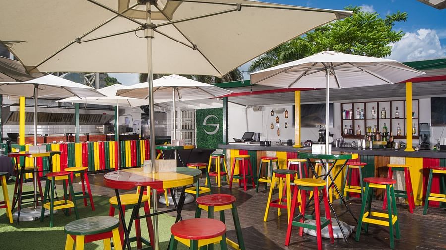 An outdoor dining setup of a restaurant in Montego Bay with sun loungers and colourful chairs - S Hotel Montego Bay, Jamaica