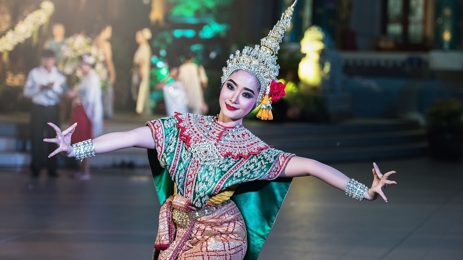 A Thai dancer in traditional attire posing for a picture while dancing.