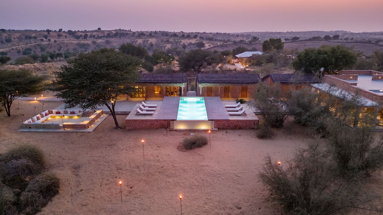 A well-lit path leads to a modern desert villa at twilight, highlighting the blend of luxury and nature - MANVAR Resort & Desert Camp