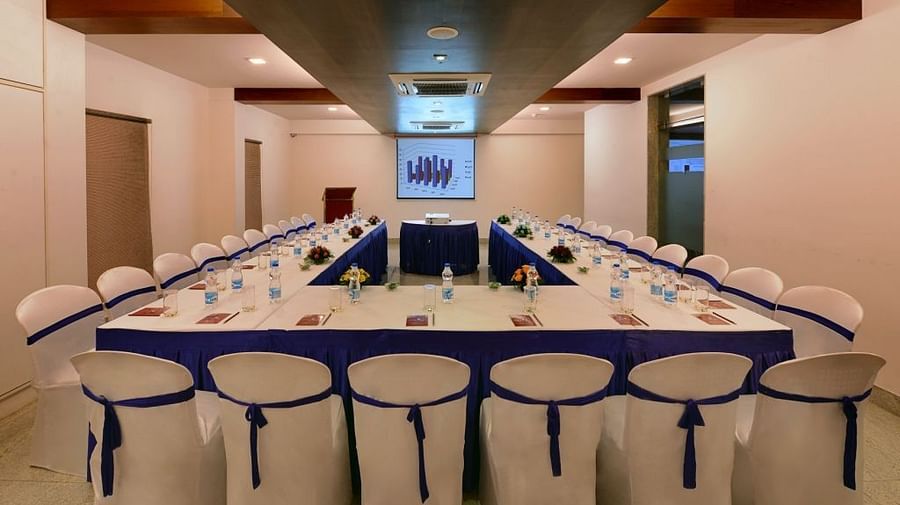 A long conference table with chairs, water bottles, and presentation materials in a meeting room with a projector screen.