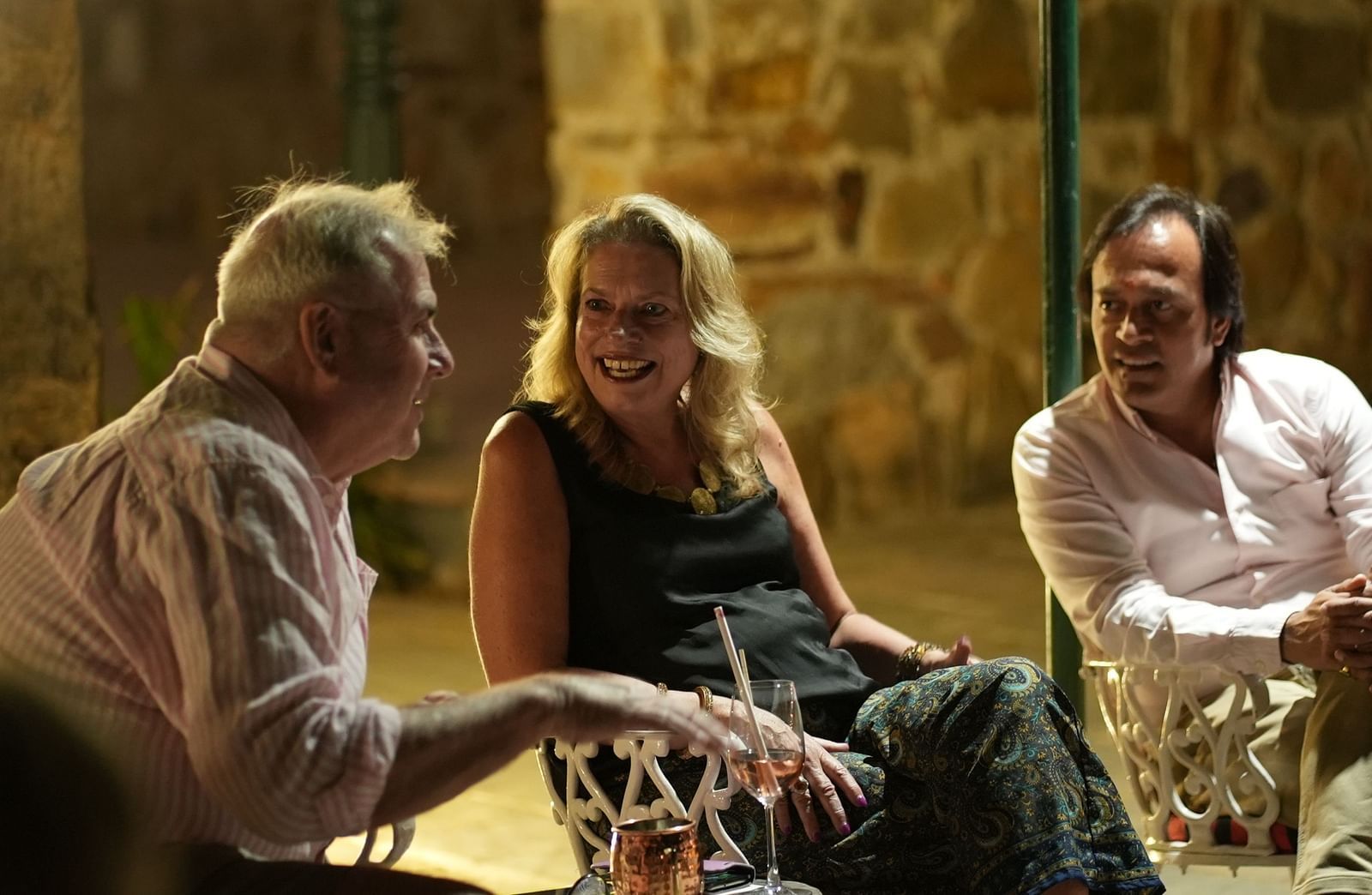 Guests share a cheerful conversation during an evening gathering in a rustic outdoor setting - Khas Bagh, Jaipur.
