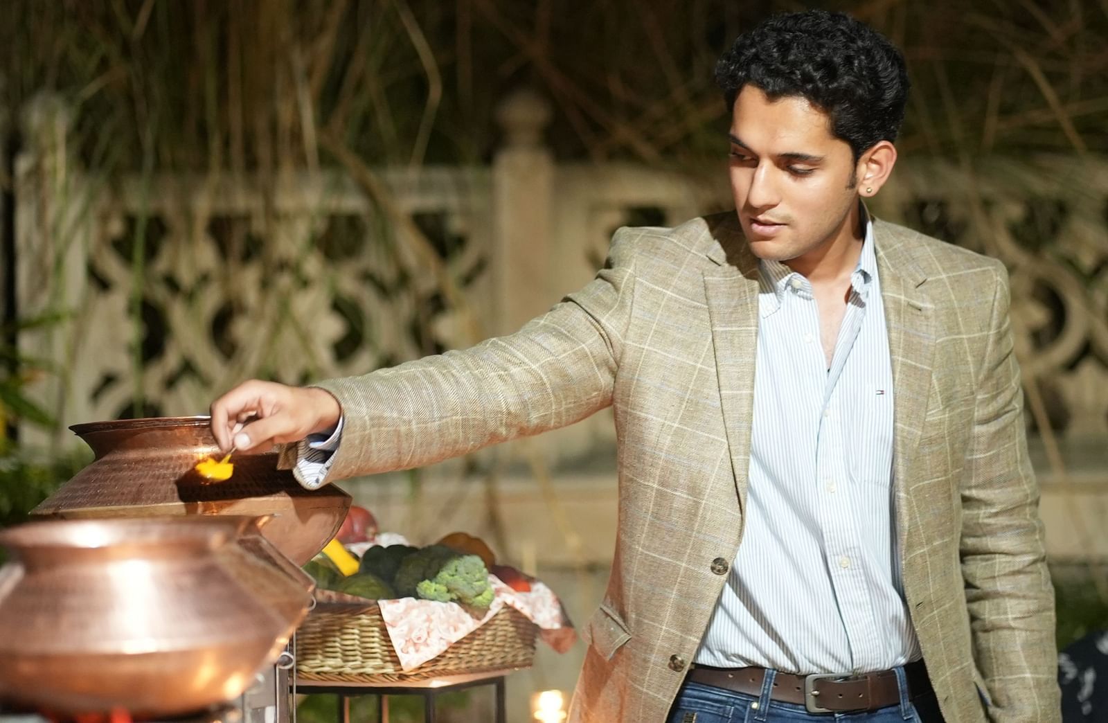 A man in a beige coat serves himself from a traditional Indian buffet setup - Khas Bagh, Jaipur.